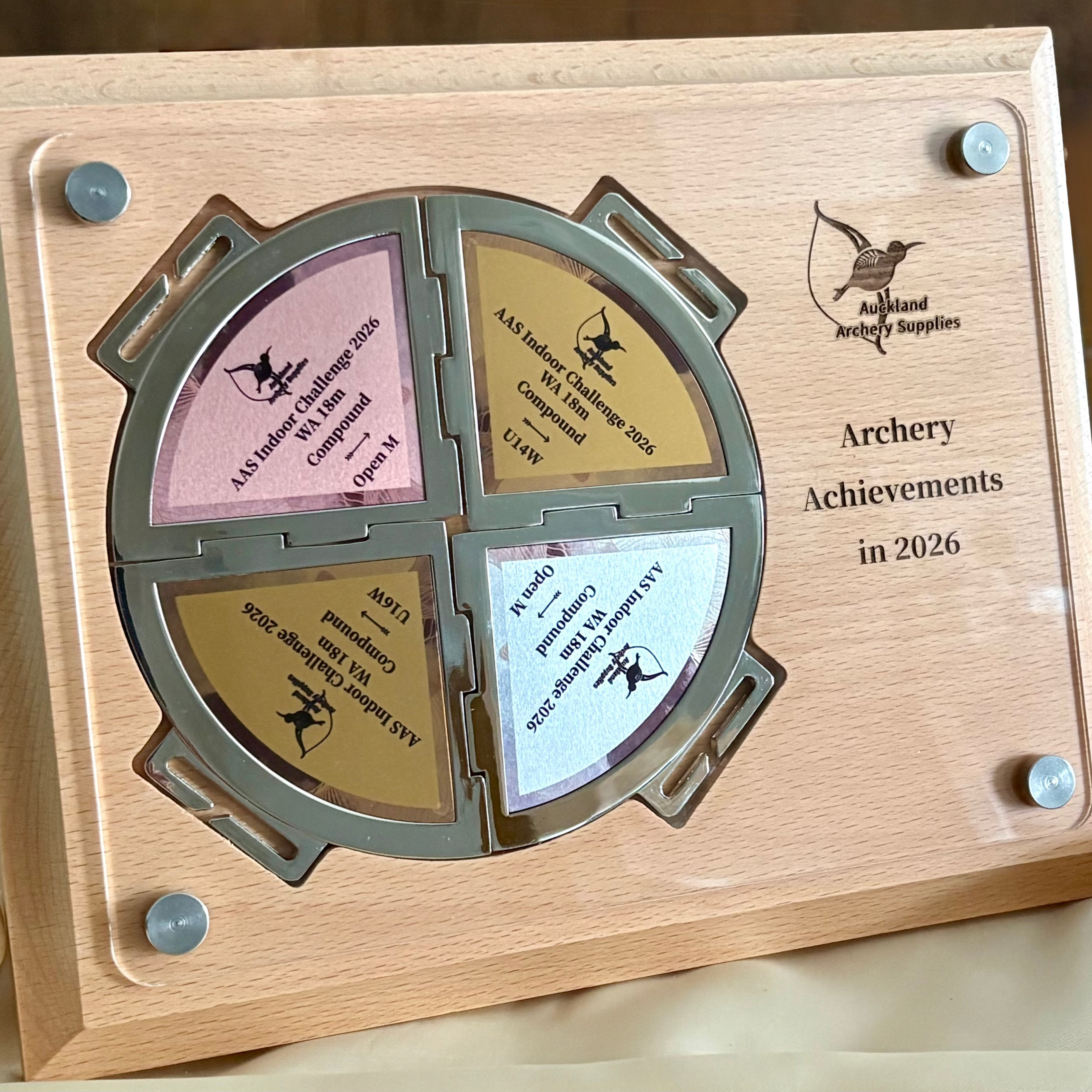 Wooden plaque with archery achievements for 2026 on a wooden surface.