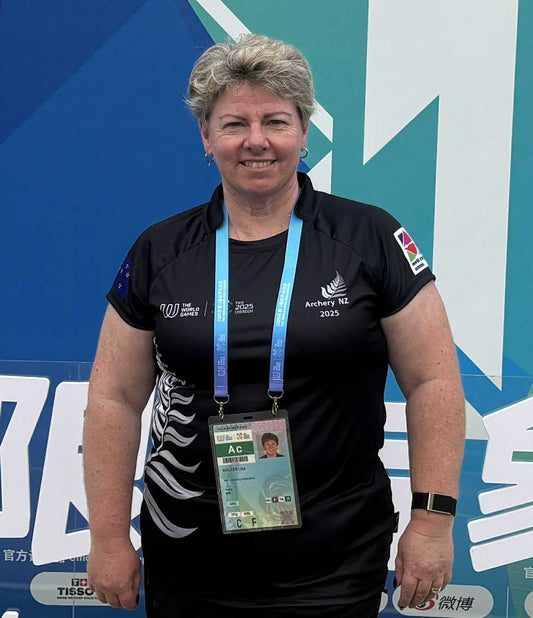 Person wearing a black shirt with logos and a lanyard with an ID card against a blue and white background.